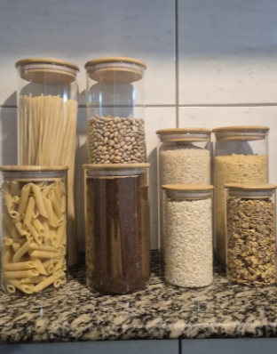 Potes de vidro com macarrão, feijão e grãos na bancada da cozinha