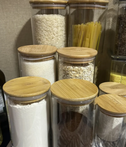 Potes de vidro com arroz, aveia e macarrão empilhados na despensa
